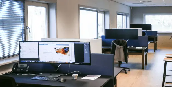 Werkplekken met schermen op het kantoor van Miller Digital