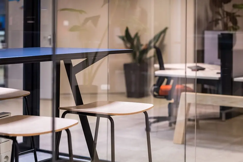 Hoge tafels achter glas op het kantoor van Miller Digital