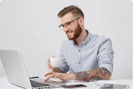 Man met een kop koffie achter een laptop